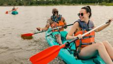 Two people kayaking in a green kayak on calm waters in Virginia Beach, Virginia, USA