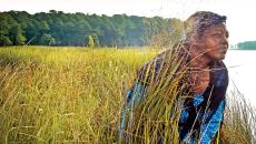 An actress portraying Harriet Tubman crouches among a field along the Harriet Tubman Underground Railroad Byway in Maryland, USA.