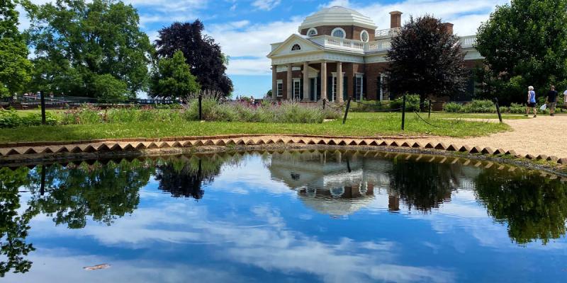 A cloud-streaked blue sky reflected in a glassy pond that sits in front of Thomas Jefferson's Monticello in Charlottesville, Virginia, USA