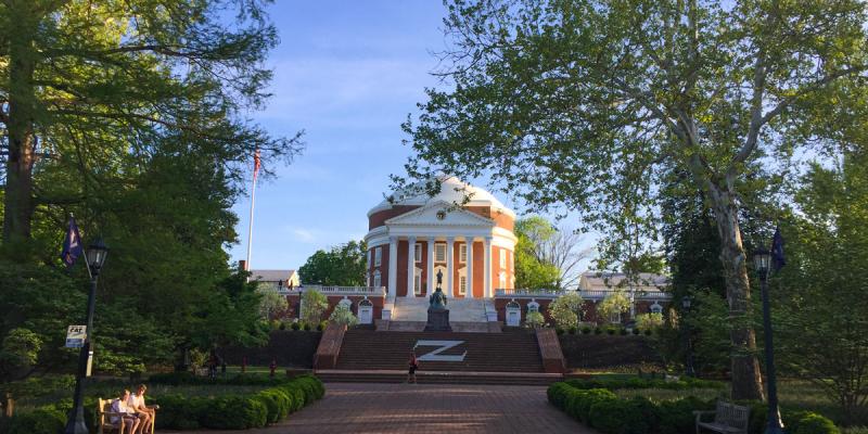 The round, red and pillared rotunda of the University of Virginia sits flanked by green trees and blue skies in Virginia, USA