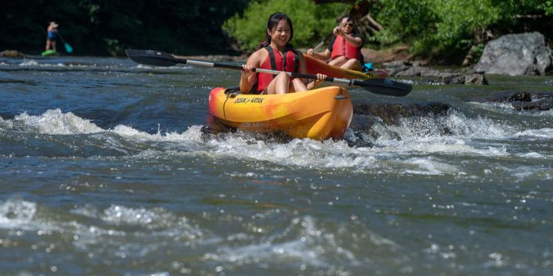 Two people in kayaks paddling over rapids in Charolottesville, Virginia, USA
