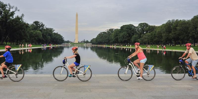 People biking past the Washington Monument on a tour with Bike &amp; Roll in Washington, DC, USA