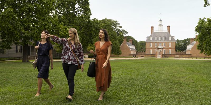 Three women walking the lawn in front of the historic building