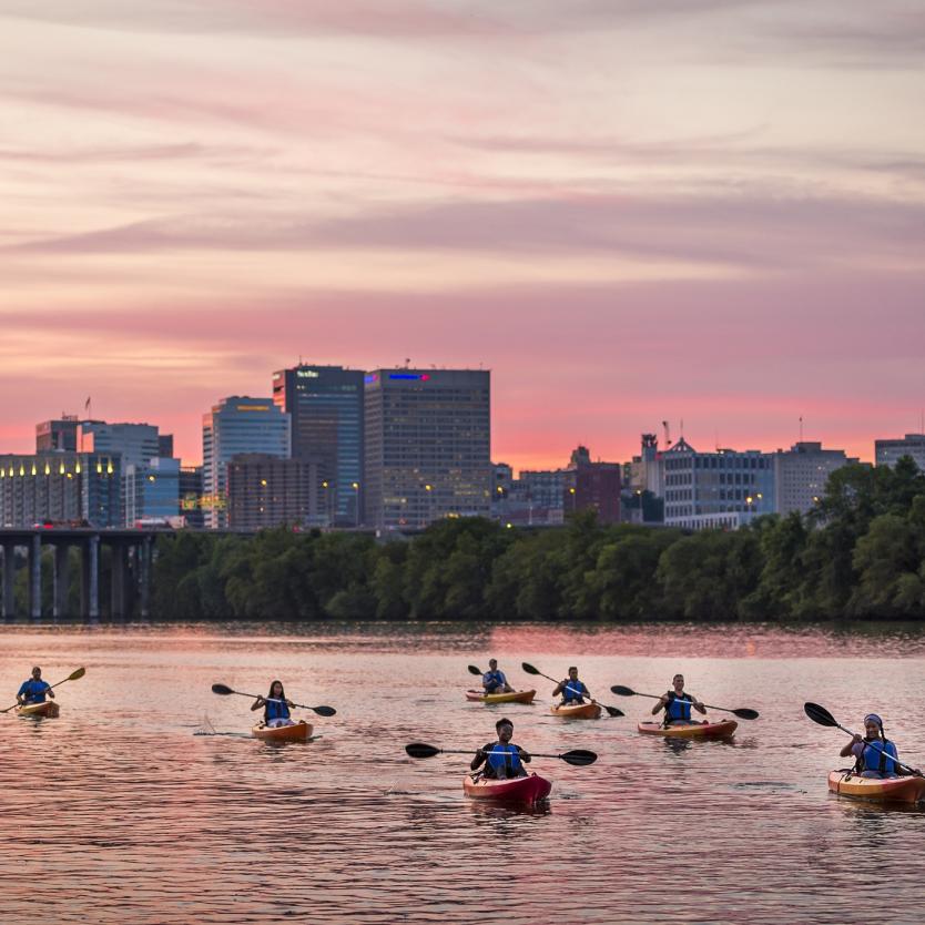 Kayakers float past the city skyline during a pink sunset in Richmond, Virginia, USA