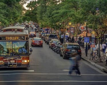 A person crossing the street in front of trolley in the King Street shopping and entertainment district of Alexandria, Virginia, USA.