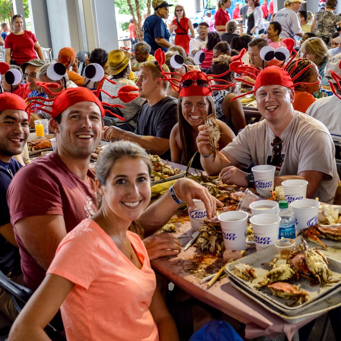 Annapolis Crab Feast_CREDIT Visit Annapolis (2).jpeg A group of people wearing crab hats enjoying the feast