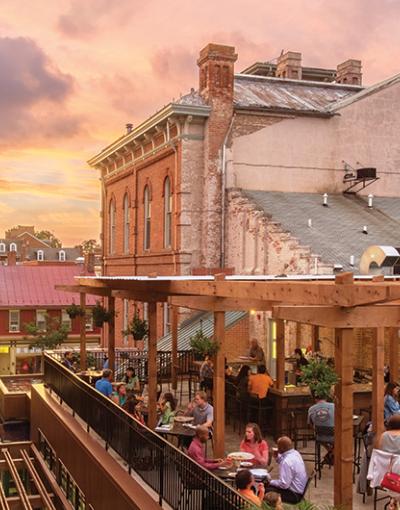 People dining during pink-tinted dusk on a rooftop in Brewer's Alley in Frederick, Maryland, USA